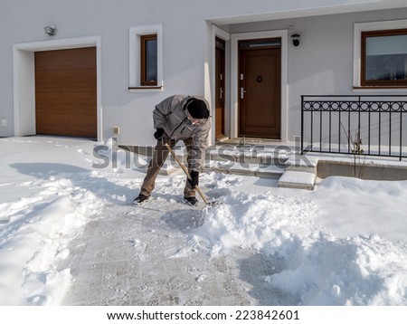 Man clearing path to his house of snow with shovel after heavy snowing