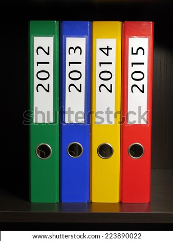 Four color binders organized by year 2012 to 2015 placed on bookshelf