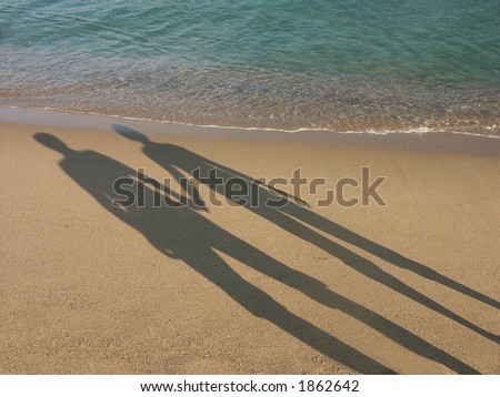 Long shadow of young couple holding 