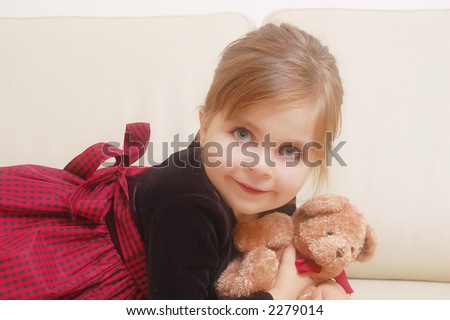 Little cute girl posing on sofa with teddy bear