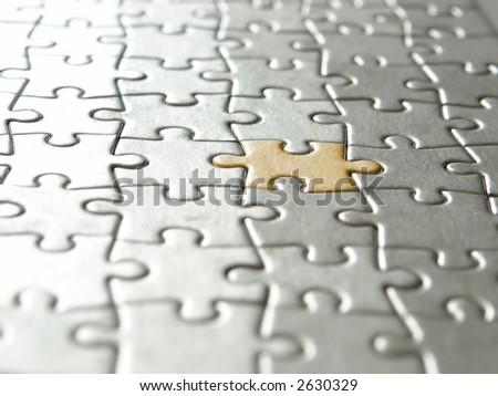 Background of silver puzzle pieces and one golden piece - selective focus