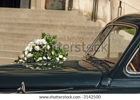Wedding flowers on retro car parked in front of church building