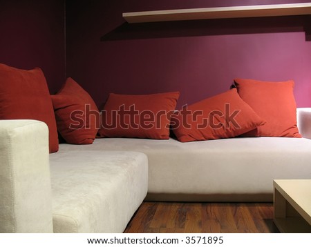 Purple wall living room with modern light beige sofa and five red pillows