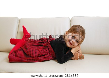 Little cute girl posing happily on sofa with her teddy bear