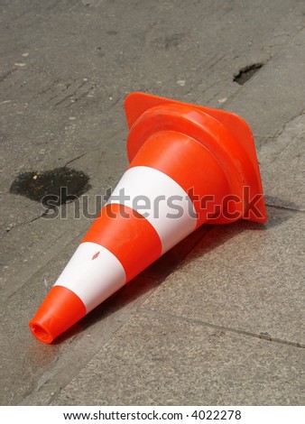 Fallen over road warning cone lying on street