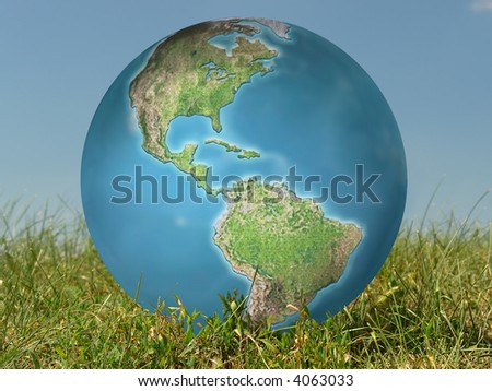 Earth globe in grass over blue sky