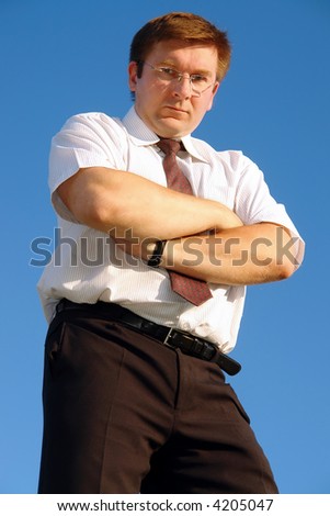 Confident businessman in white shirt and tie posing against clear blue sky