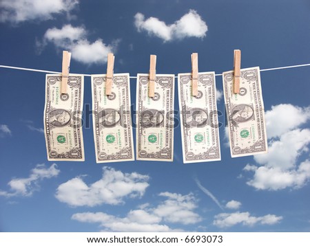One dollar bills hanging on laundry line attached with wooden clips over blue sky