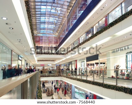 Shoppers doing christmas shopping in big shopping center decorated with christmas ornaments and lights