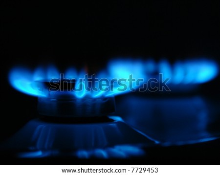Closeup of two gas cooker burners lit in the darkness