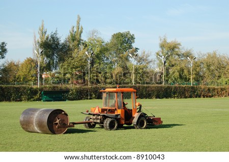 Tractor leveling soccer field grass using heavy metal lawn roller