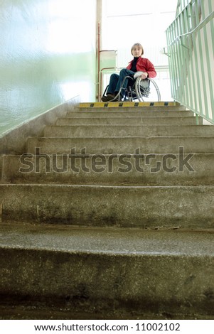 Handicapped woman on wheelchair looking down the stairs in building staircase