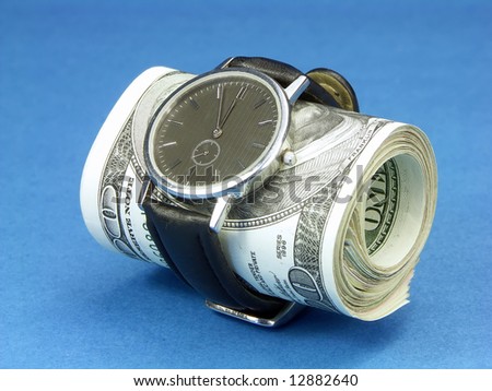 Wrist watch wrapped around a roll of 100 us dollar banknotes over blue background