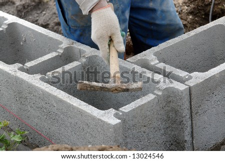 Construction worker hammering out cuts made in concrete blocks for placing reinforcement