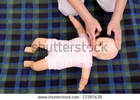 Infant dummy first aid demonstration series - First aid instructor showing how to position infant head before proceeding to mouth-to-mouth resuscitation - view from above