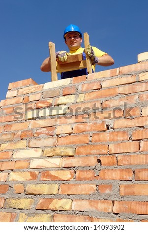 Construction worker standing on wooden ladder resting on brick wall