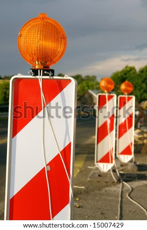 Red and white striped road warning posts with orange beacons