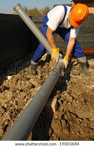 Plumber assembling pvc sewage pipes in house foundation