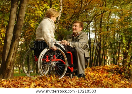 Husband and handicapped wife spending time together in park in fall time