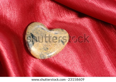 Marble heart-shaped stone placed on crimson fabric