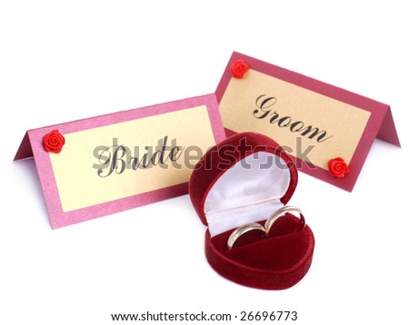 Wedding rings in red suede box and Bride and Groom name cards over white