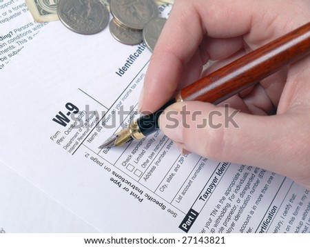 Closeup of female hand filling out W-9 income tax form with pen