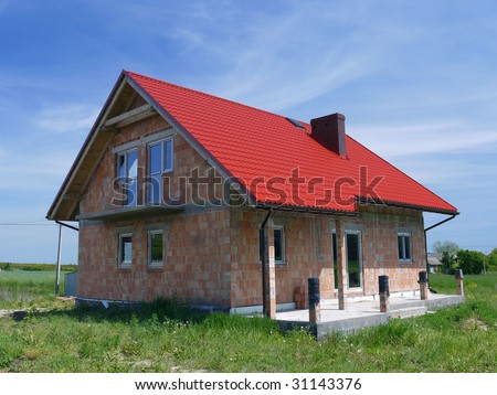 Unfinished single-family brick house covered by red sheet metal roof