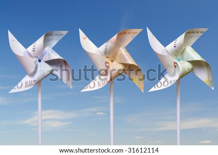 Three toy windmills cut from 100, 50 and 20 euro banknotes over blue sky