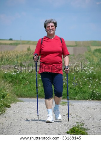 Senior woman practicing nordic walking in the countryside
