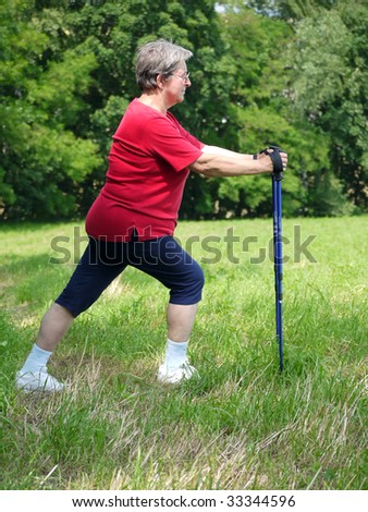 Senior woman doing a series of warm-up exercises with walking poles
