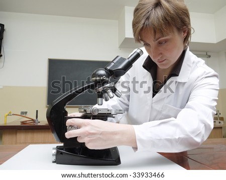 Female biology teacher preparing microscope for the lesson