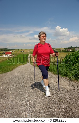 Senior woman doing nordic walking in the countryside