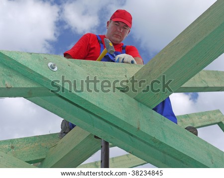 Roofer driving a nail into house rafter beam