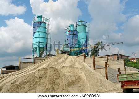 Concrete batching plant with three silos, heap of sand and gravel
