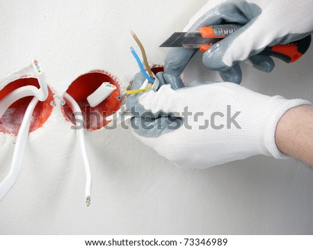 Closeup of electrician\'s hands stripping electrical wires for wall socket
