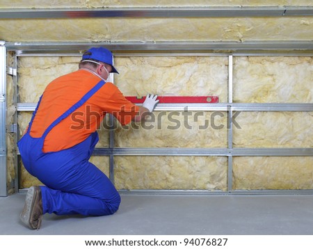 Construction worker thermally insulating house attic with mineral wool