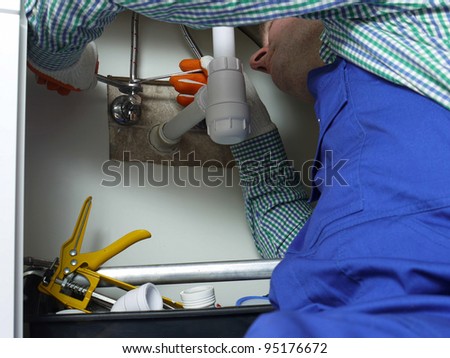 Plumber installing cold and hot water fixtures to bathroom washbasin