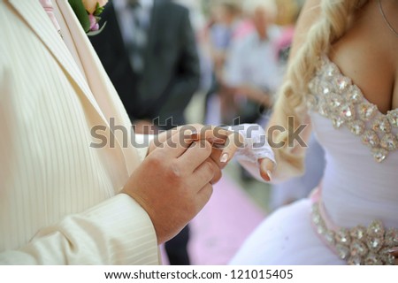 groom puts wedding ring on bride\'s finger