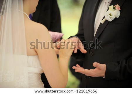 bride puts wedding ring on groom\'s finger