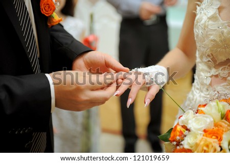 groom puts wedding ring on bride\'s finger