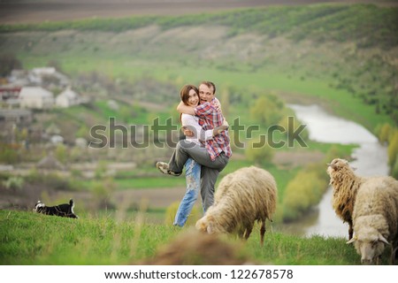 man embraces his girlfriend being afraid of sheep