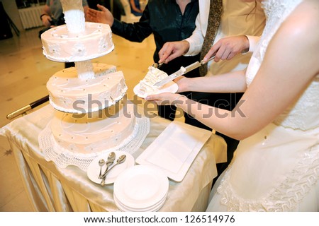 bride and groom holding hands cutting cake