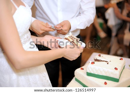 bride and groom holding hands cutting cake