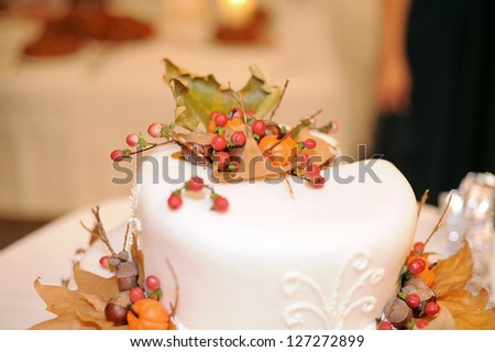 cake decorated with dry leaves, pumpkin and red berries