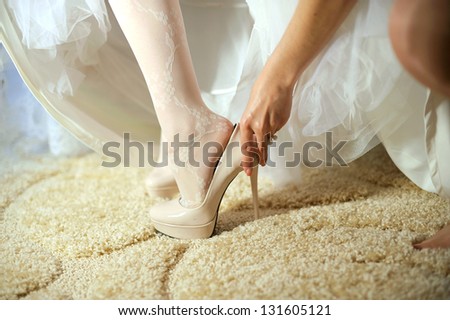 bridesmaid helping bride to put on shoe