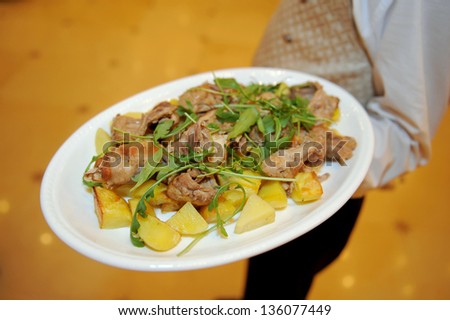 waiter holding plate with chicken and potato