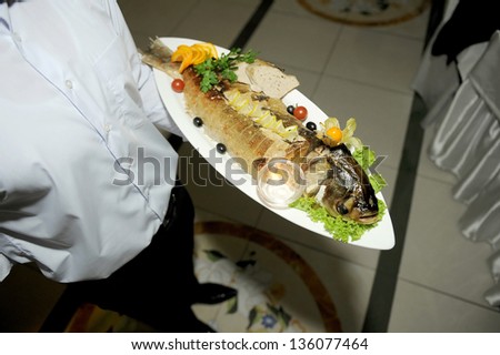 waiter holding decorated plate with fish