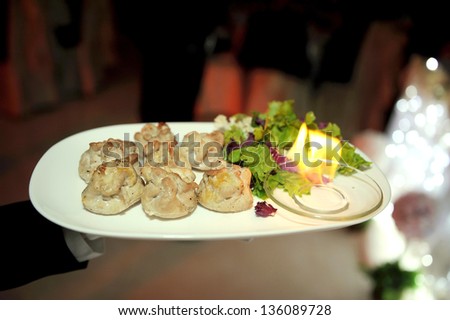 waiter holding plate with chicken and fire in bowl