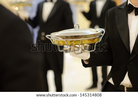 waiter serving dish with candles in restaurant