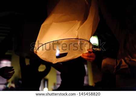 man holding flying lantern with fire